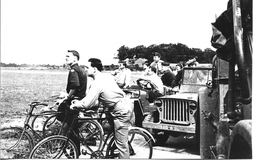 A photo of men on bicycles and in a jeep