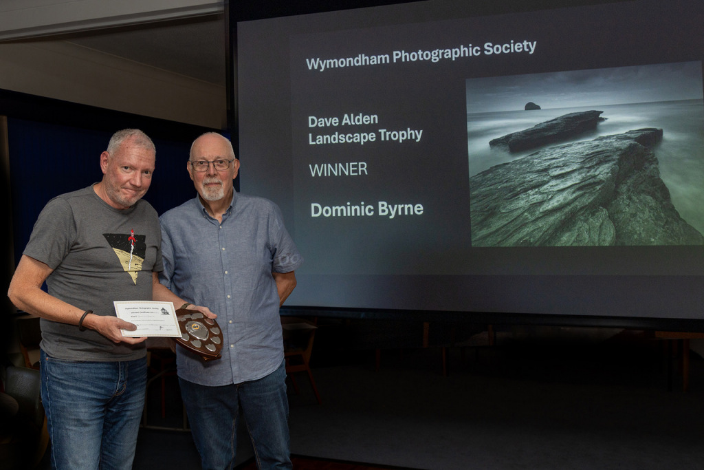 Two men shaking hands holding an award