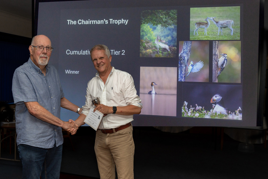 Two men shaking hands holding an award