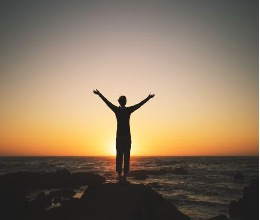 Man holding his arms up against the sunset