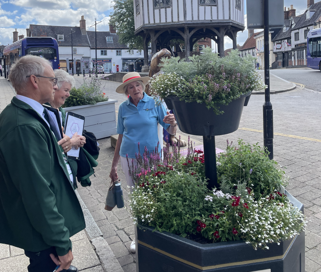 A woman shows two judges a flower display