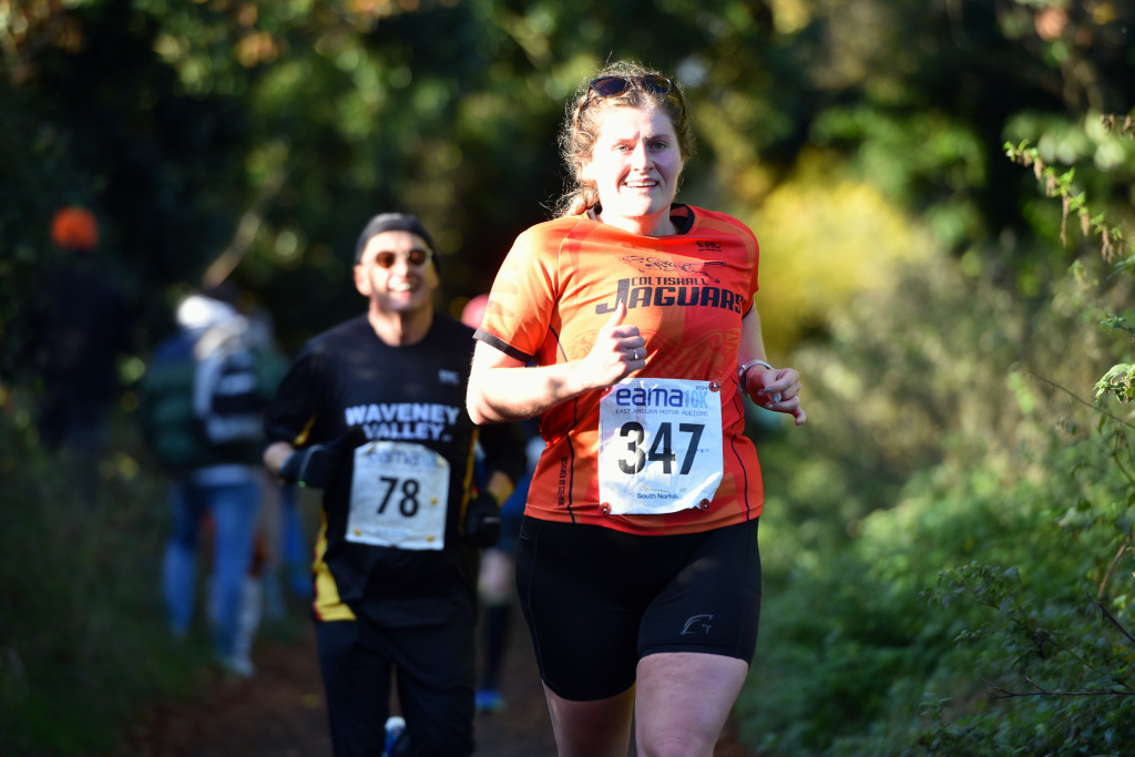 A woman running with other runners trailing her