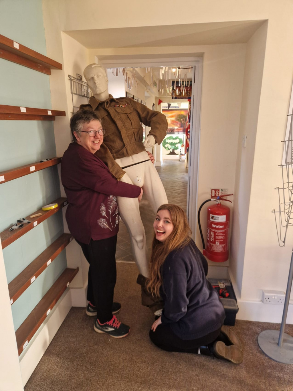 Two amused women holding a mannequin