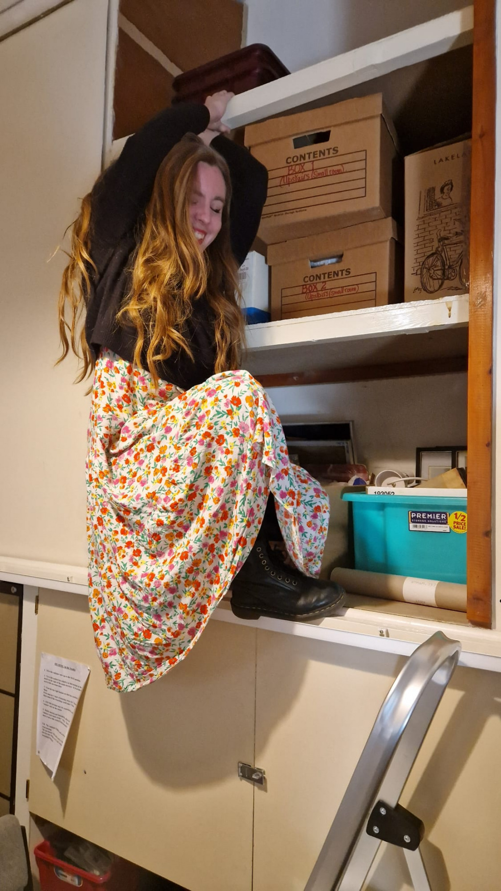 Woman hanging from a shelf by her fingertips