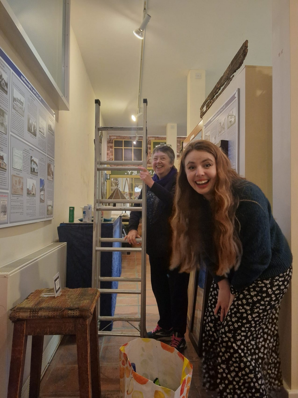 Two laughing women about to climb a ladder
