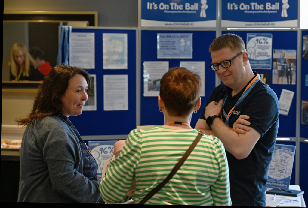 A man speaking with two women at a stall