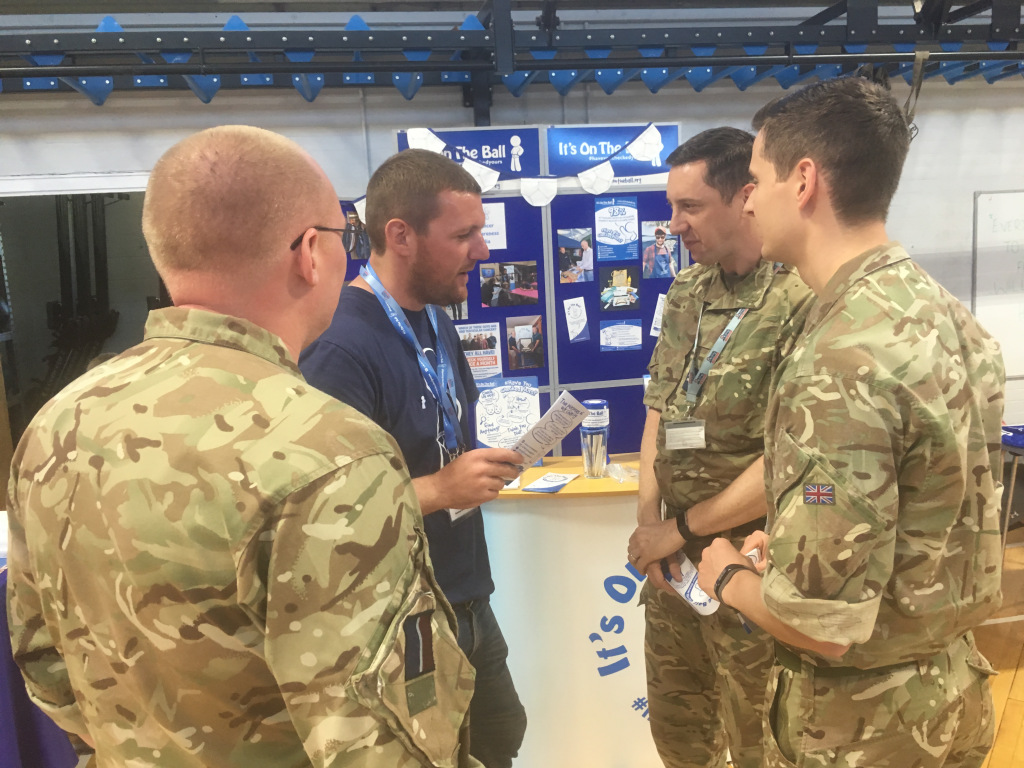 A man talking with three young men in army suits