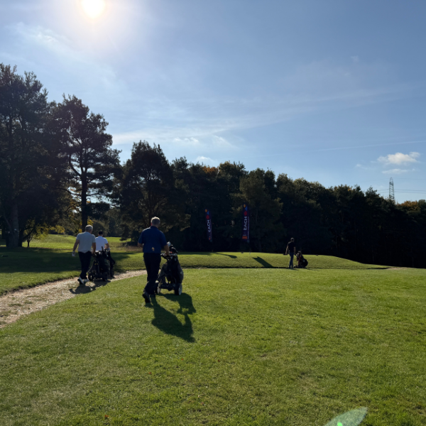 People walking down the sunlit golf course