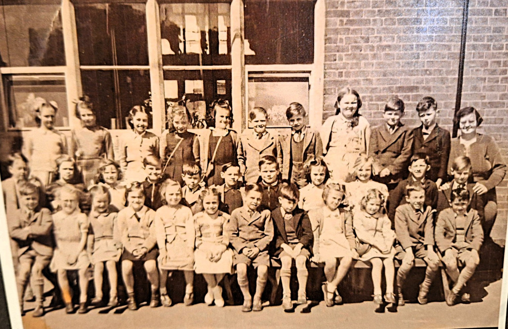 Sepia photo of a teacher sitting with her pupils outside