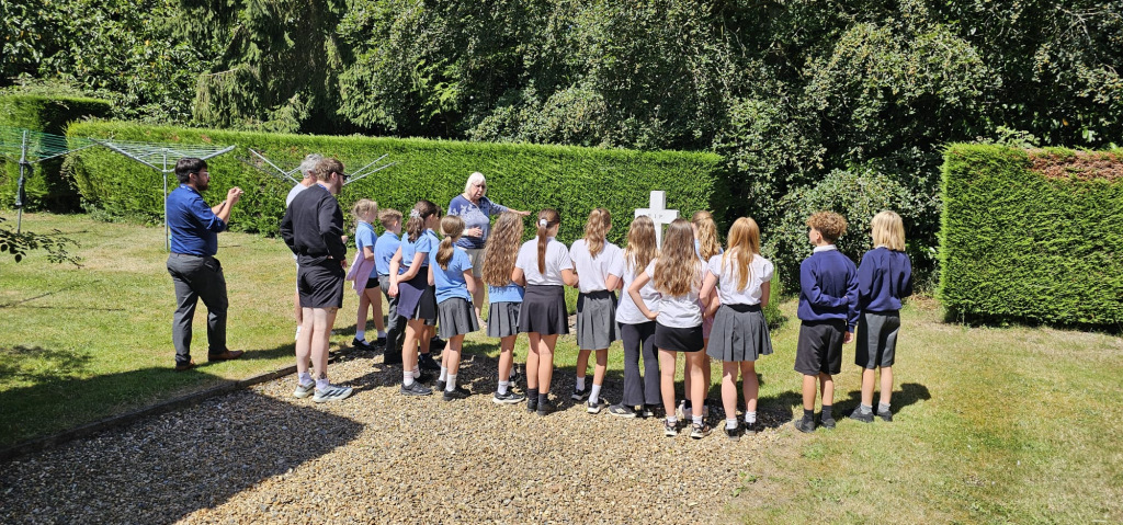 Woman standing with children explaining something by a gravestone