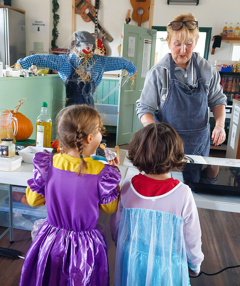 Kids in fancy dress being taught cooking by lady chef