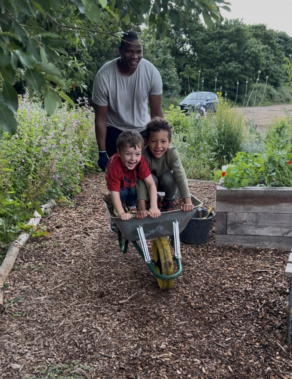 A man pushing two children on a wheelbarrow