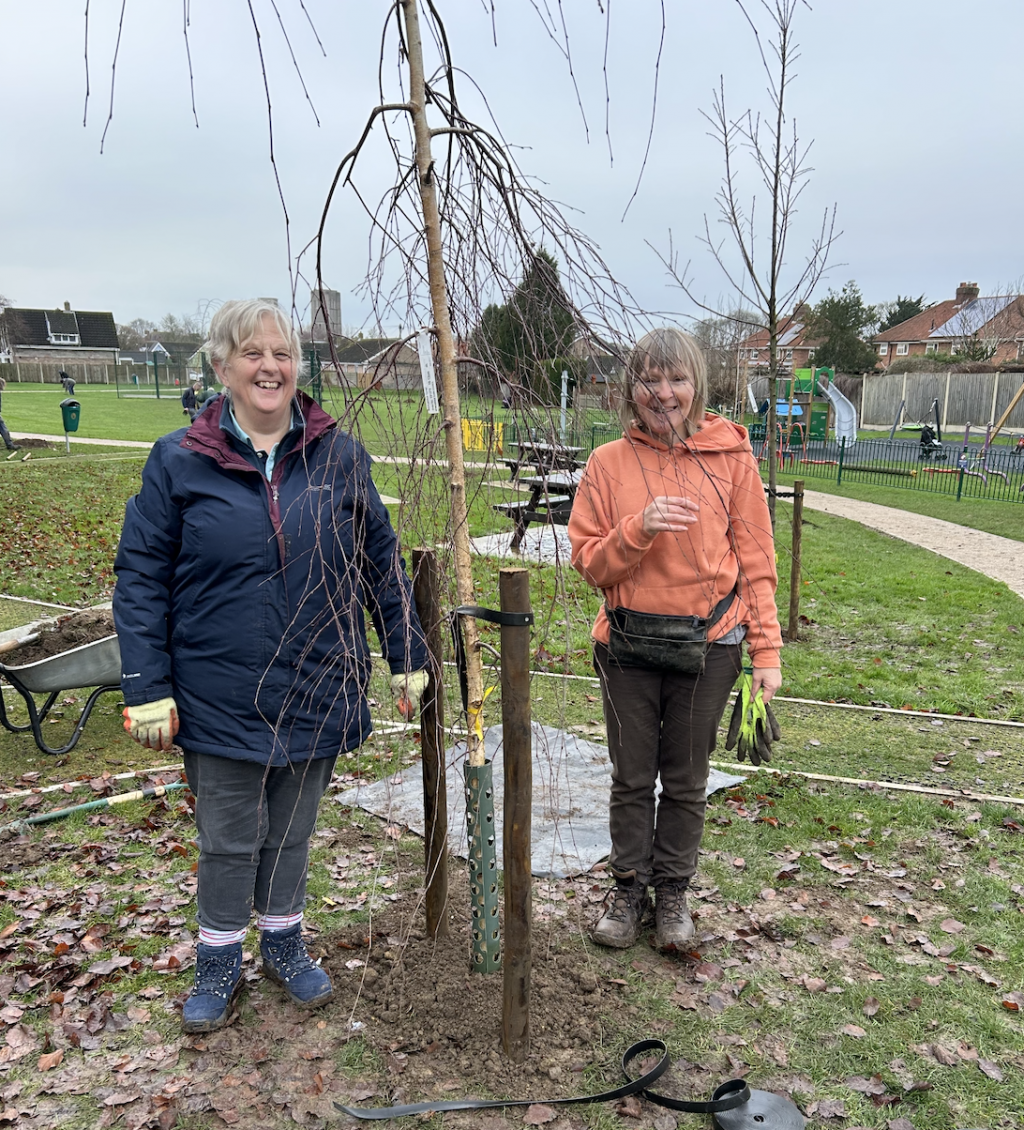 Two women standing by a tree