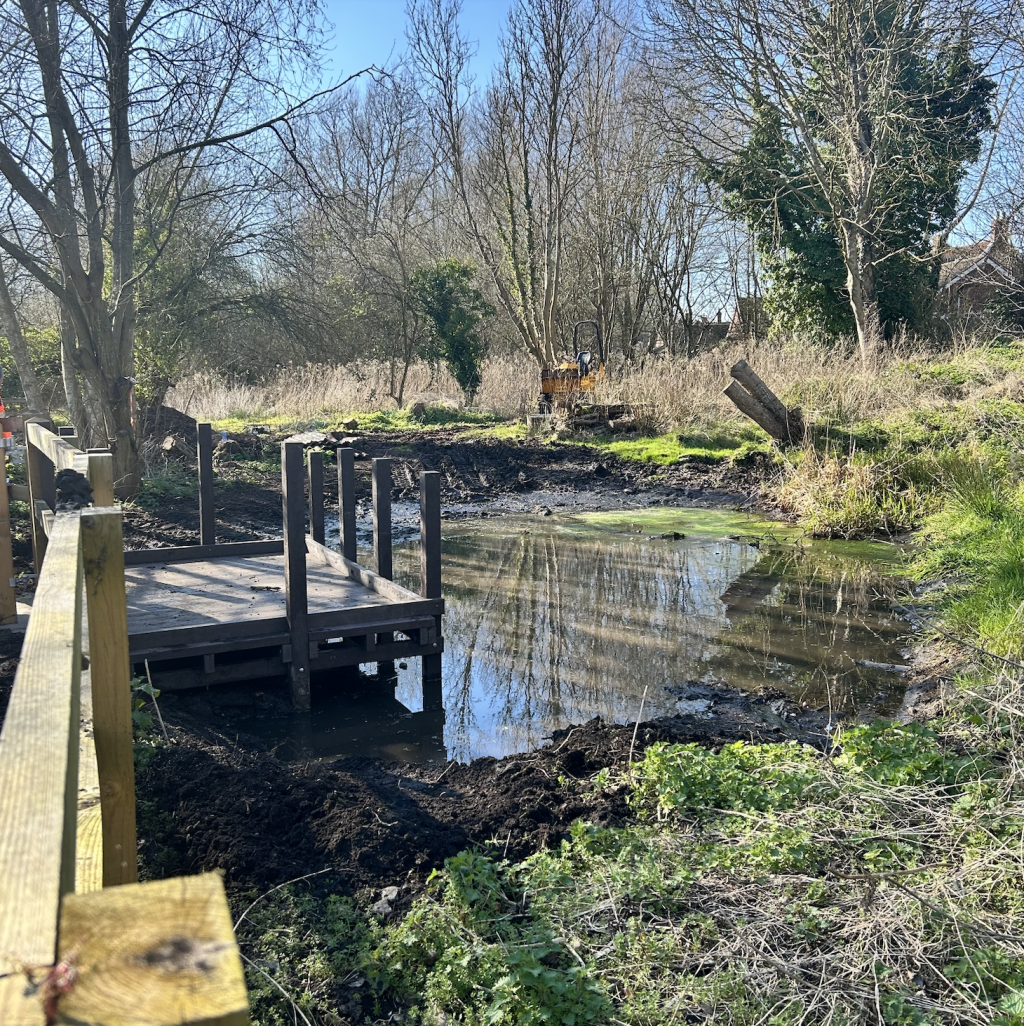 A fenced quay looking out over a pond