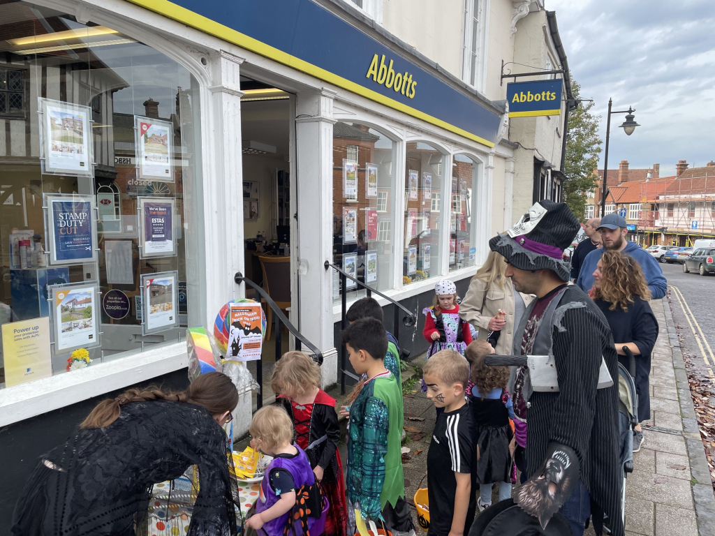 group of kids trick or treating outside estate agent in costumes