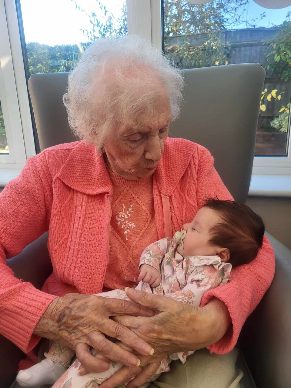Elderly lady holds sleeping infant