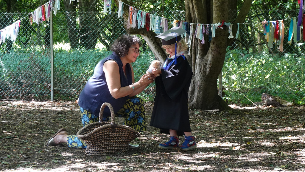 Child in a graduation outfit standing with a teacher