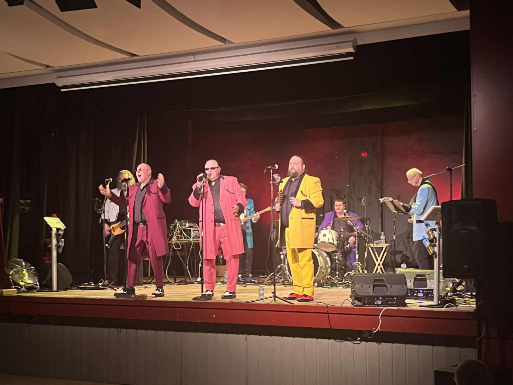 Four men onstage in coloured suits