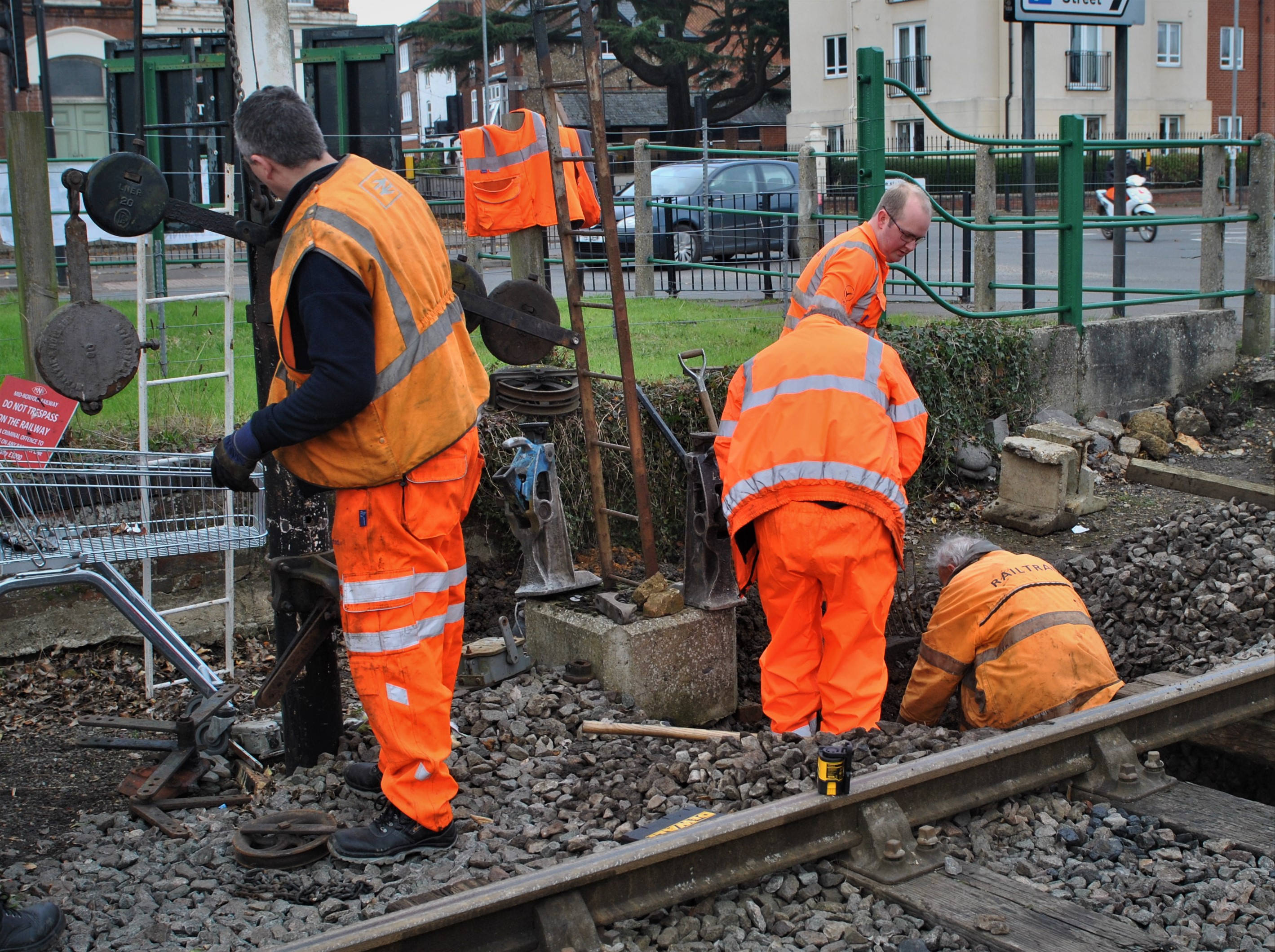 Men in orange hi vis work on side of railway
