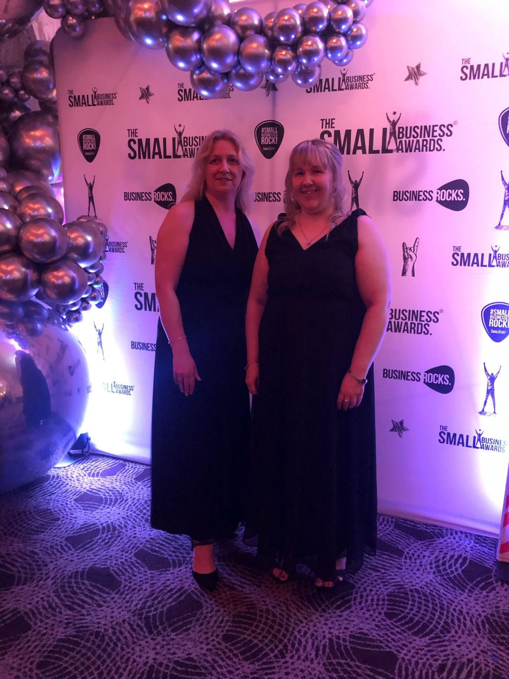 Two ladies in black dresses at awards event