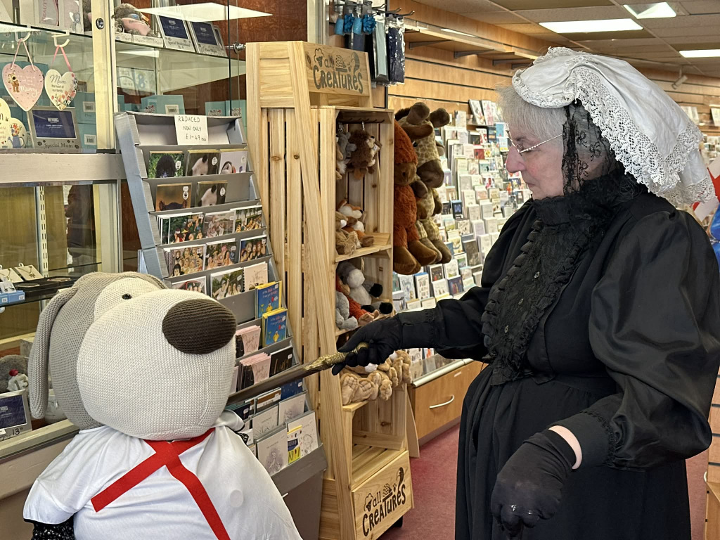 Queen Victoria dresser-upper looking at a shopping shelf of cards