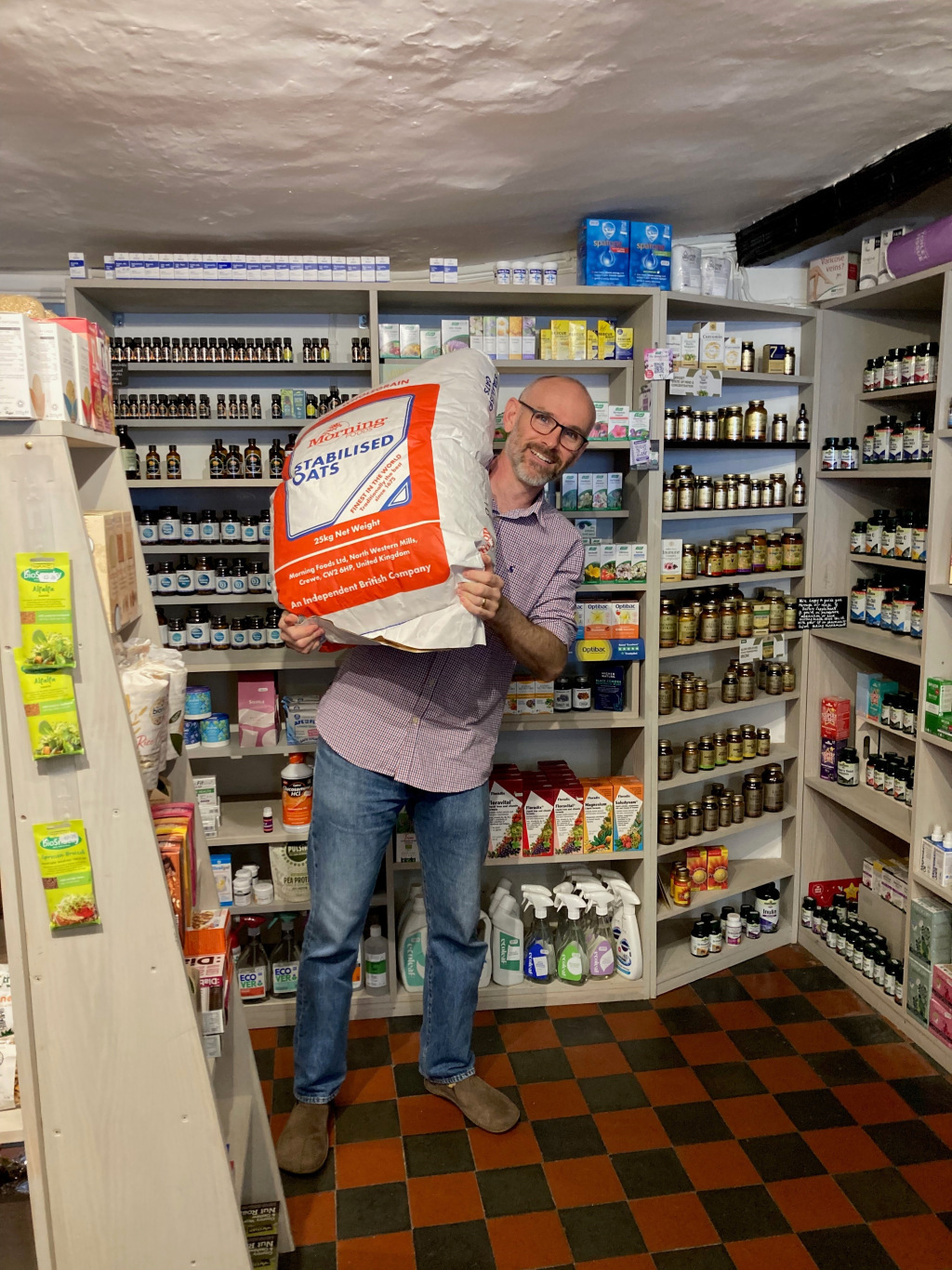 Man holds large sack of oats in shop