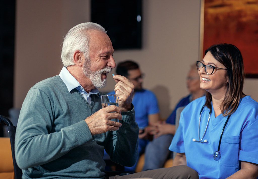 An elderly man sitting with a nurse and smiling