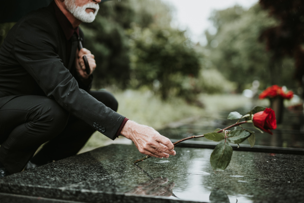 Man laying a poppy on a grave