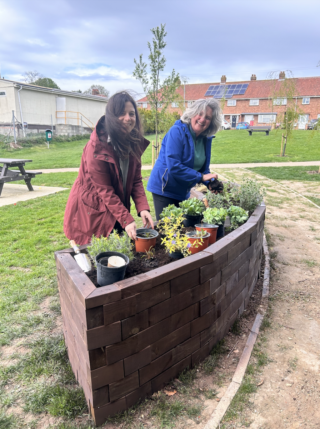 Two women by standing by several pots of plants