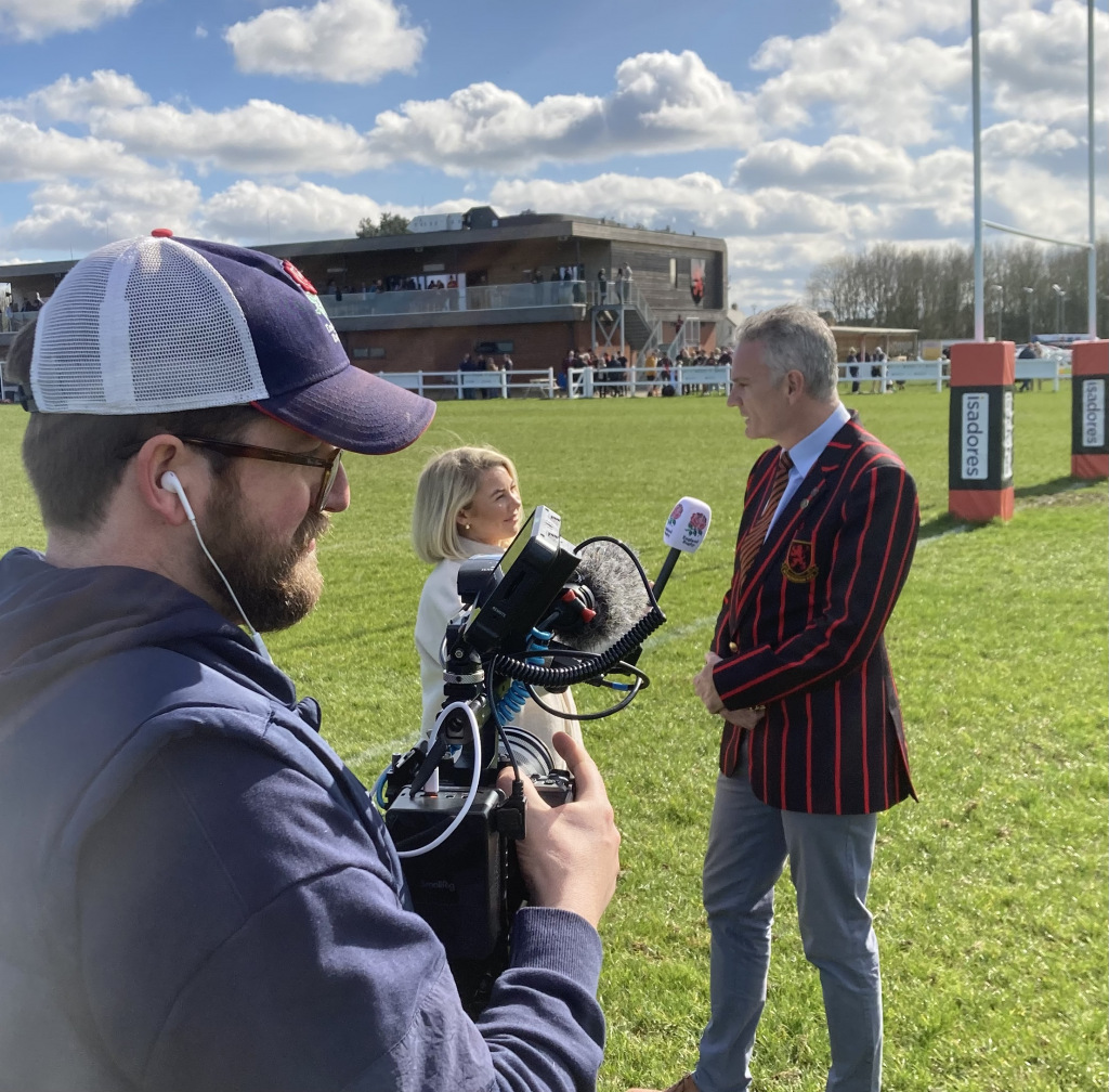 Film crew interviews man on rugby pitch