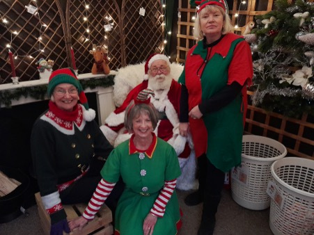 A man dressed as Santa surrounded by women dressed as elves