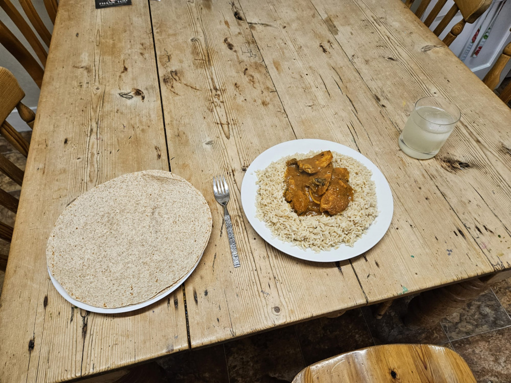 Two plates of rice; one plain, another topped with curry