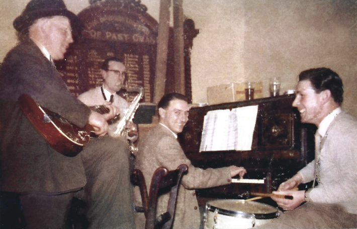 Four men sitting around a keyboard