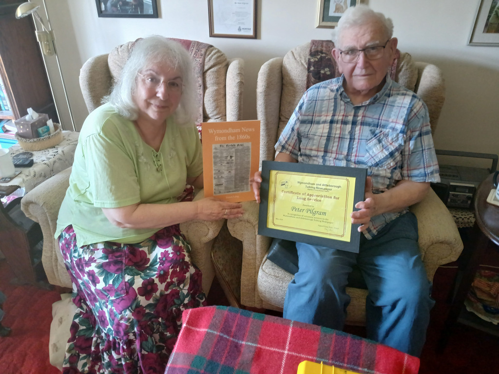 Man and a woman on armchairs, the man holding a certificate