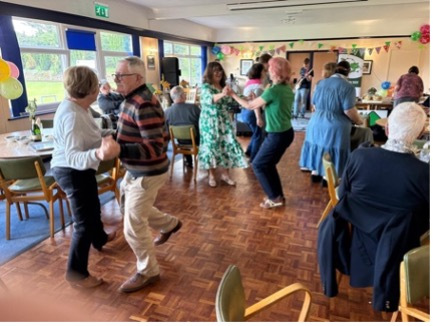 A room full of elderly folk dancing