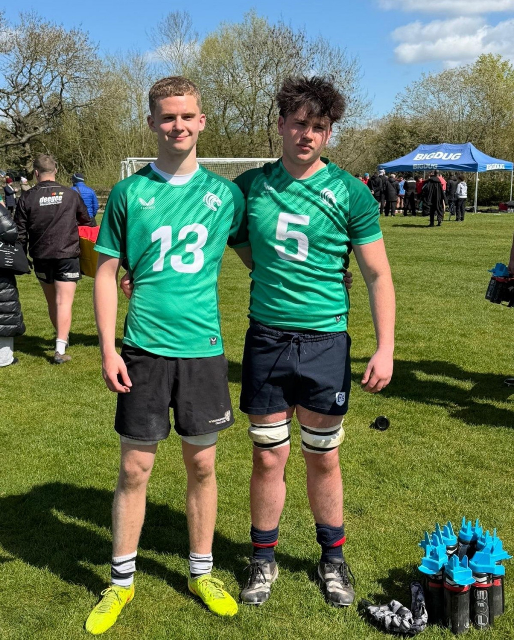 Two boys standing side by side on a sports field