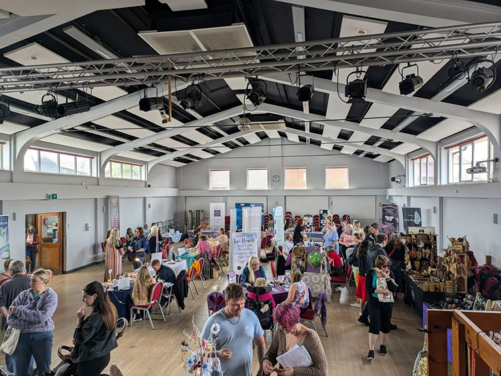 Hall full of people and stalls holding a wellbeing fair