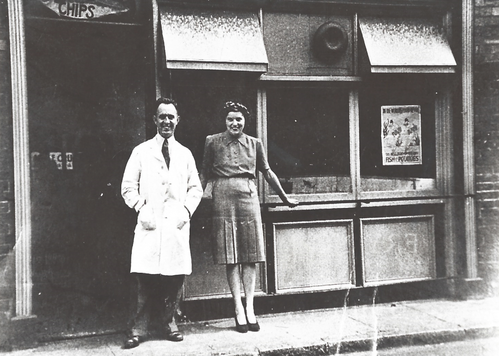 Black and white photo of couple in front of shop