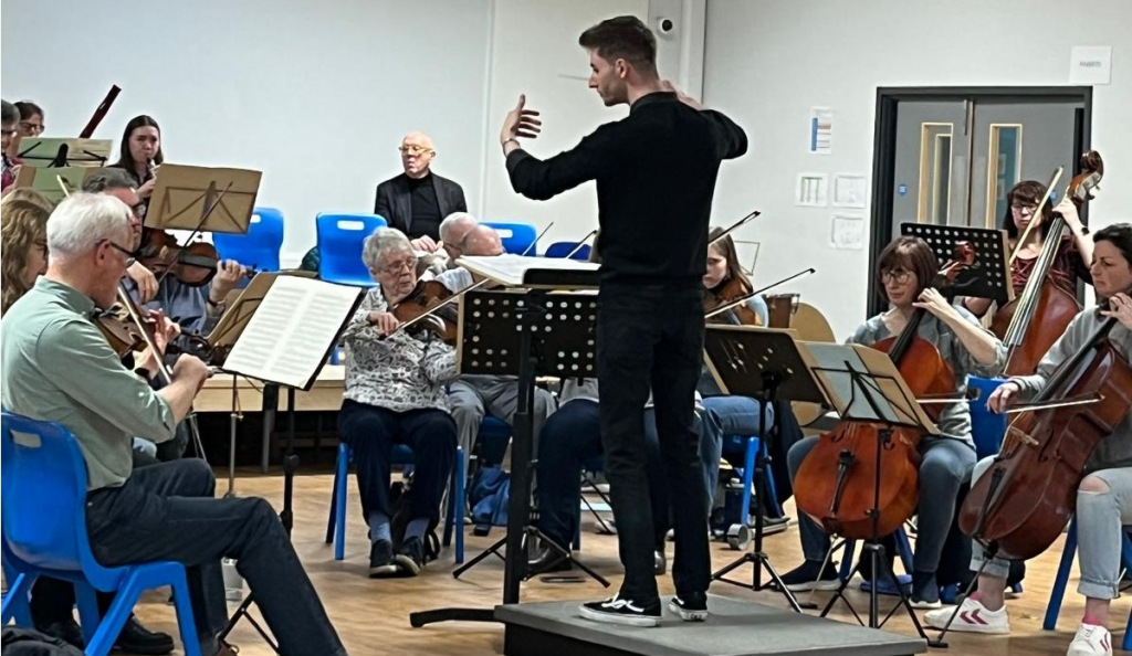 A conductor standing in front of an orchestra