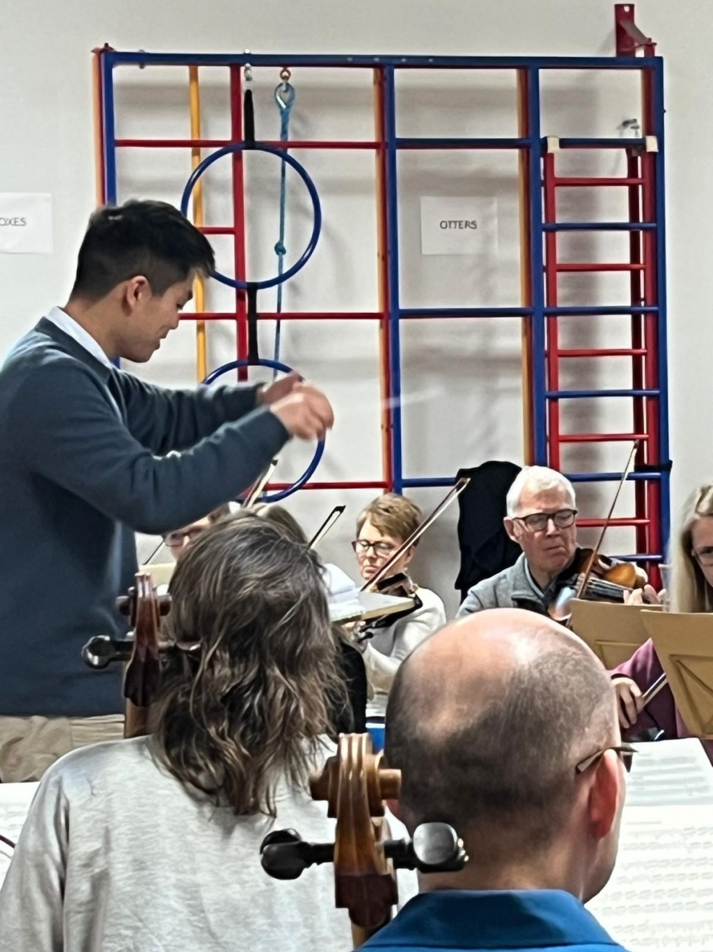 A conductor in a school gym standing in front of musicians