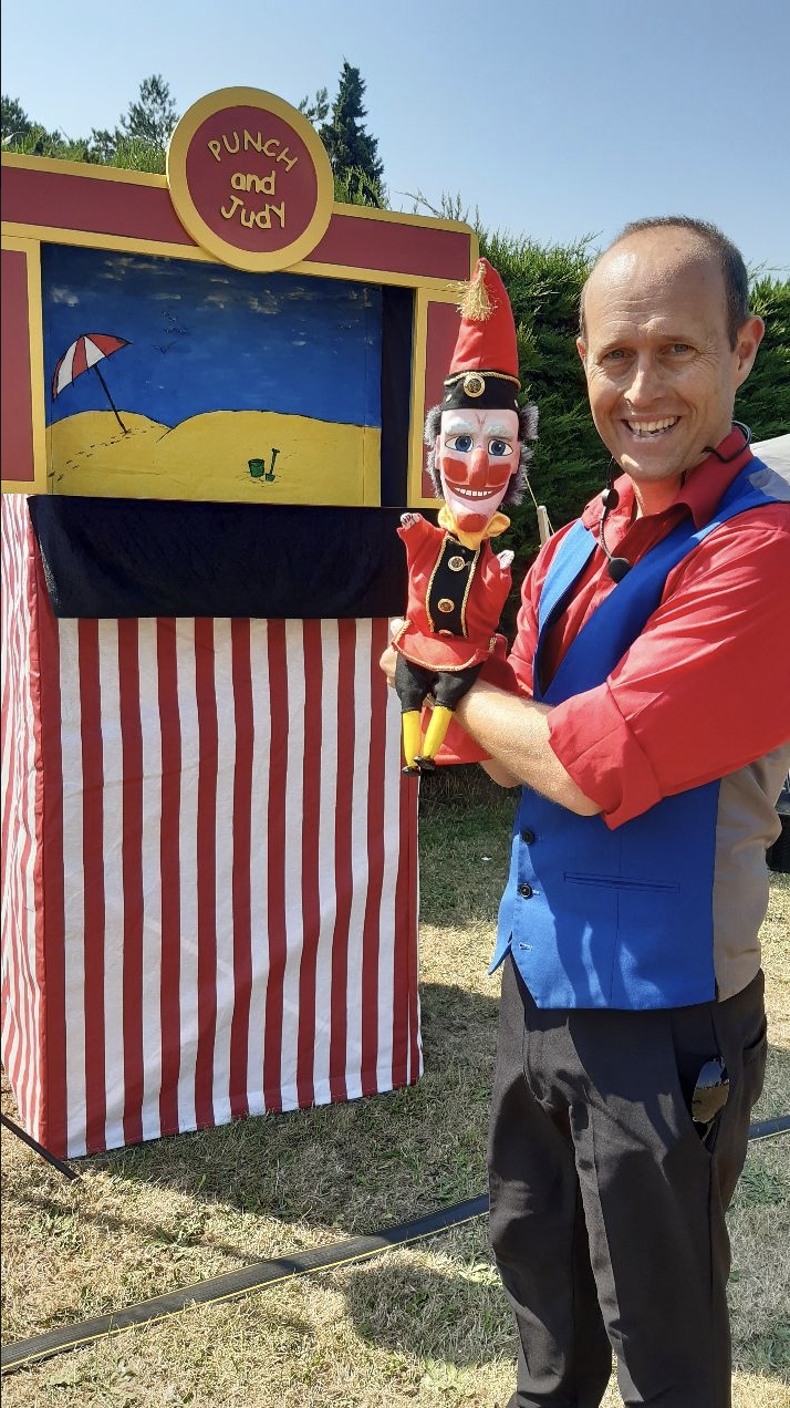 Man holding a clown puppet outside a ventriloquist