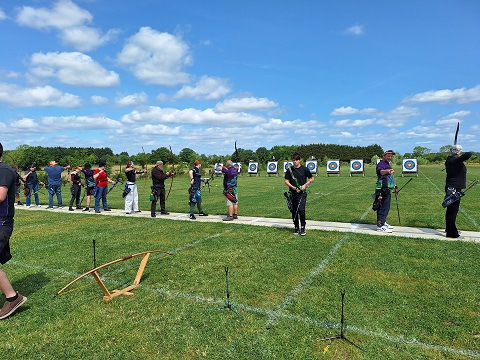 People doing archery on a sunny field