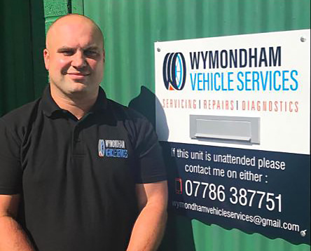 Man standing in front of a 'Wymondham Vehicle Services' sign
