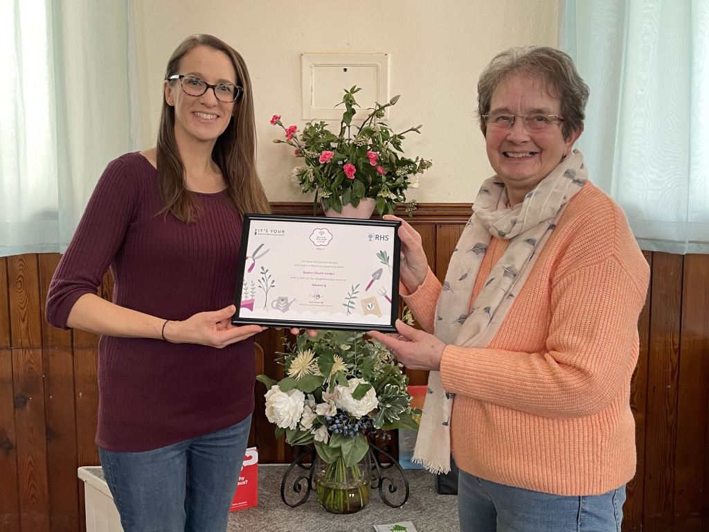 Two women holding an award for the Baptist Church garden